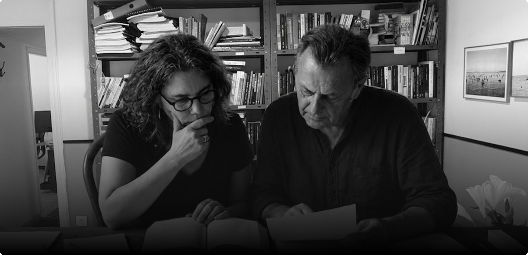 ענת זלצר ומודי בר-און יושבים יחד מול ספרייה, מעיינים בחומרים